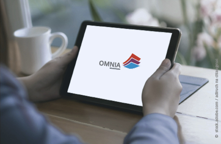 OMNIA Testversion ausprobieren Zwei Hände halten ein Tablet, darauf ist das OMNIA Logo zu sehen