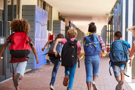 Schmuckbild: Kinder von hinten, die in die Schule kaufen
