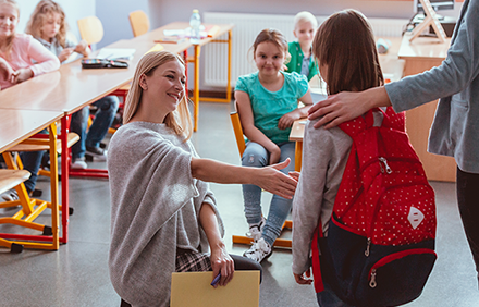 Schulkind begrüßt an ihrem ersten Schultag ihre Lehrerin